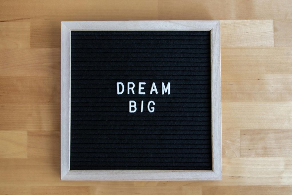 A wooden framed black letter board with the inspirational message Dream Big in white letters.
